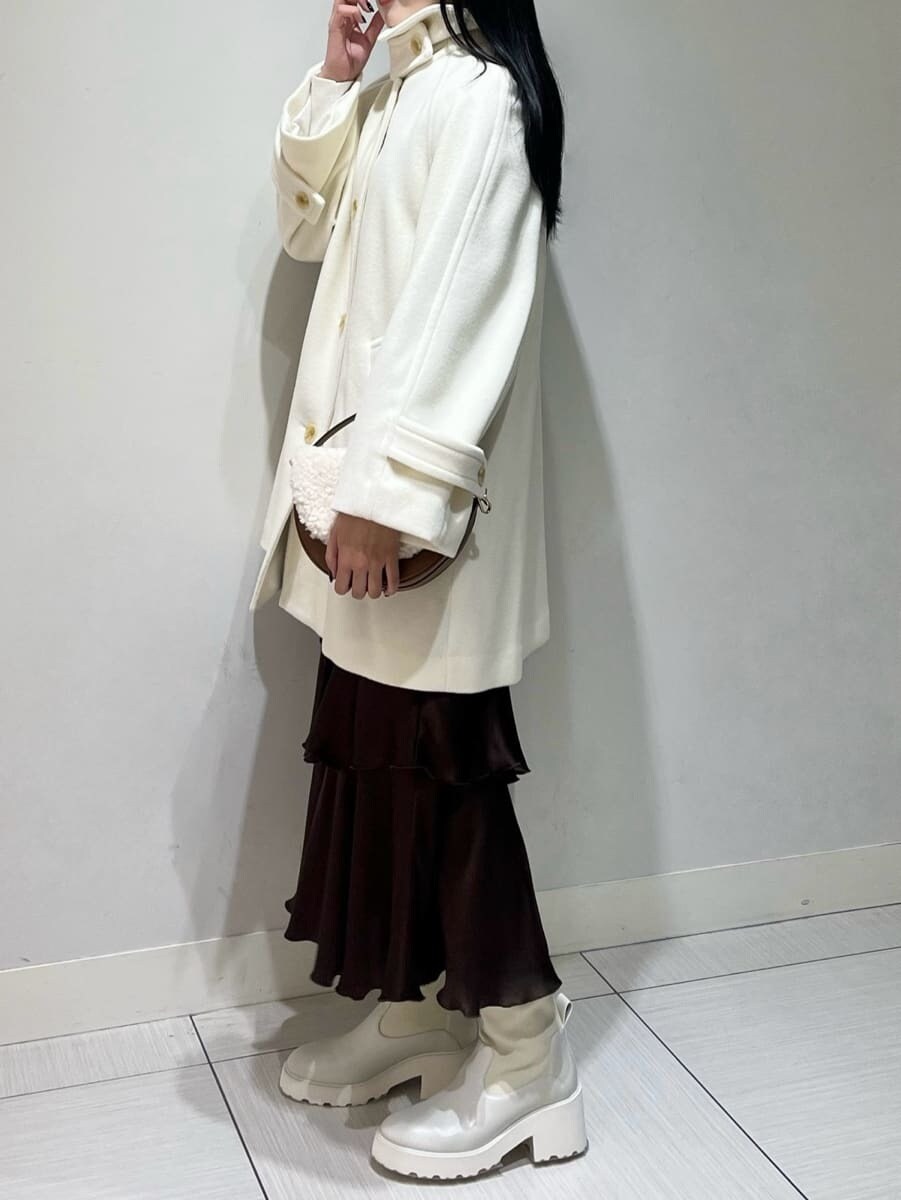 ホワイト系のニット/セーター、ブラウン系のスカート、ホワイト系のステンカラーコートを着用したレディースの秋コーディネートの2枚目の写真