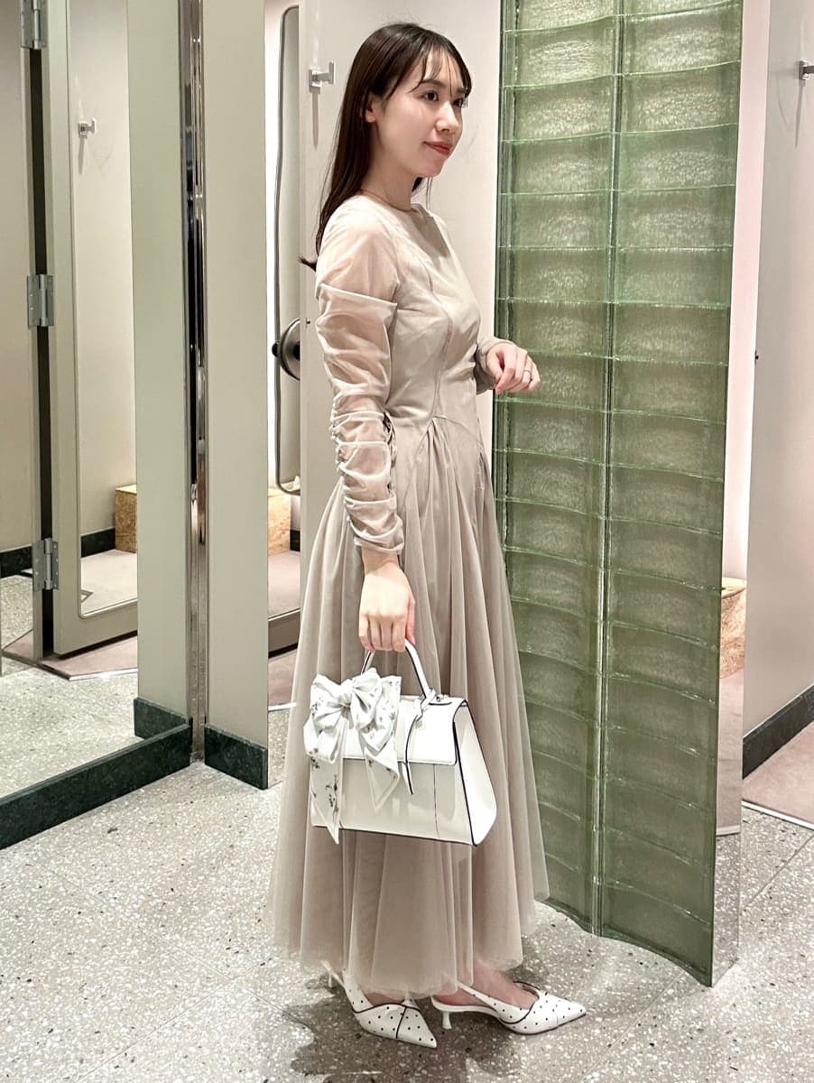 グレー系のドレス、その他のパンプス、ホワイト系のハンドバッグを着用したレディースの冬コーディネートの2枚目の写真