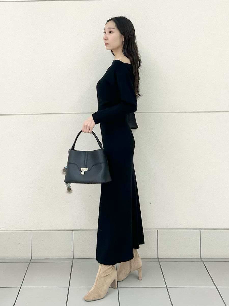 ベージュ系のブーツ、ブラック系のハンドバッグ、ブラック系のワンピースを着用したレディースの冬コーディネートの3枚目の写真