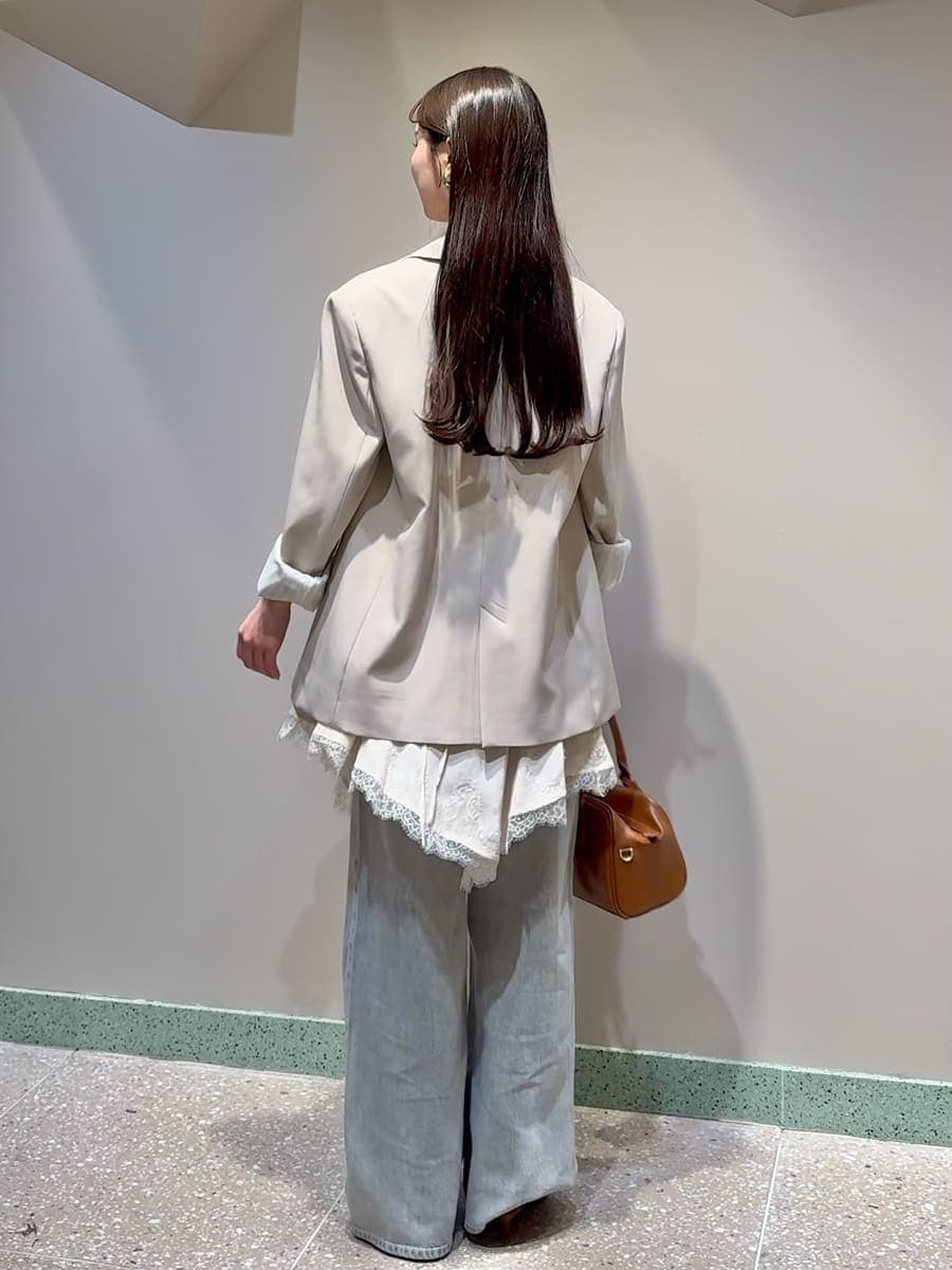 ベージュ系のテーラードジャケット、グレー系のデニムパンツ、ホワイト系のキャミソールを着用したレディースの春コーディネートの2枚目の写真