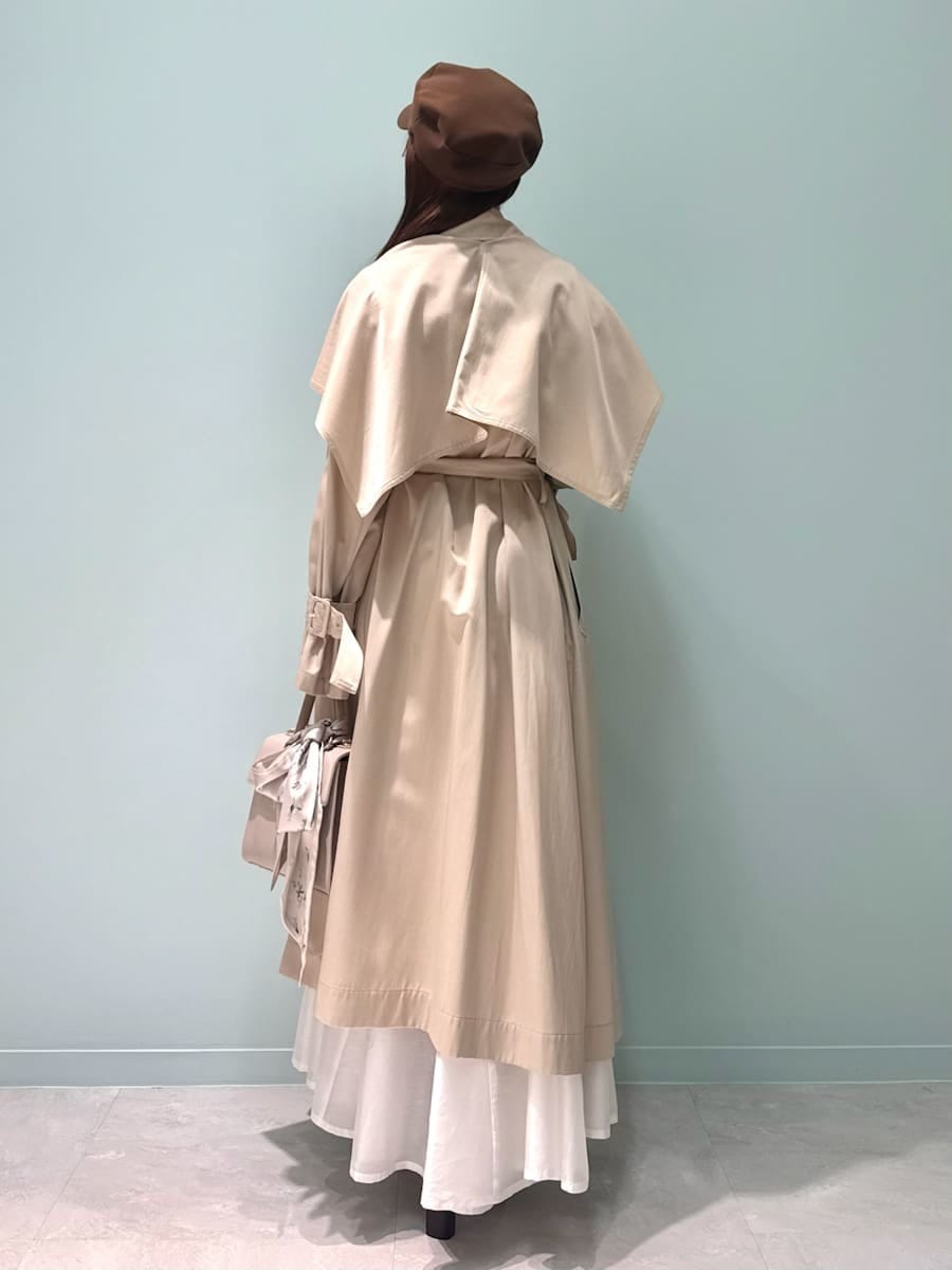 レッド系のブーツ、ベージュ系のトレンチコート、ベージュ系のハンドバッグを着用したレディースの冬コーディネートの2枚目の写真