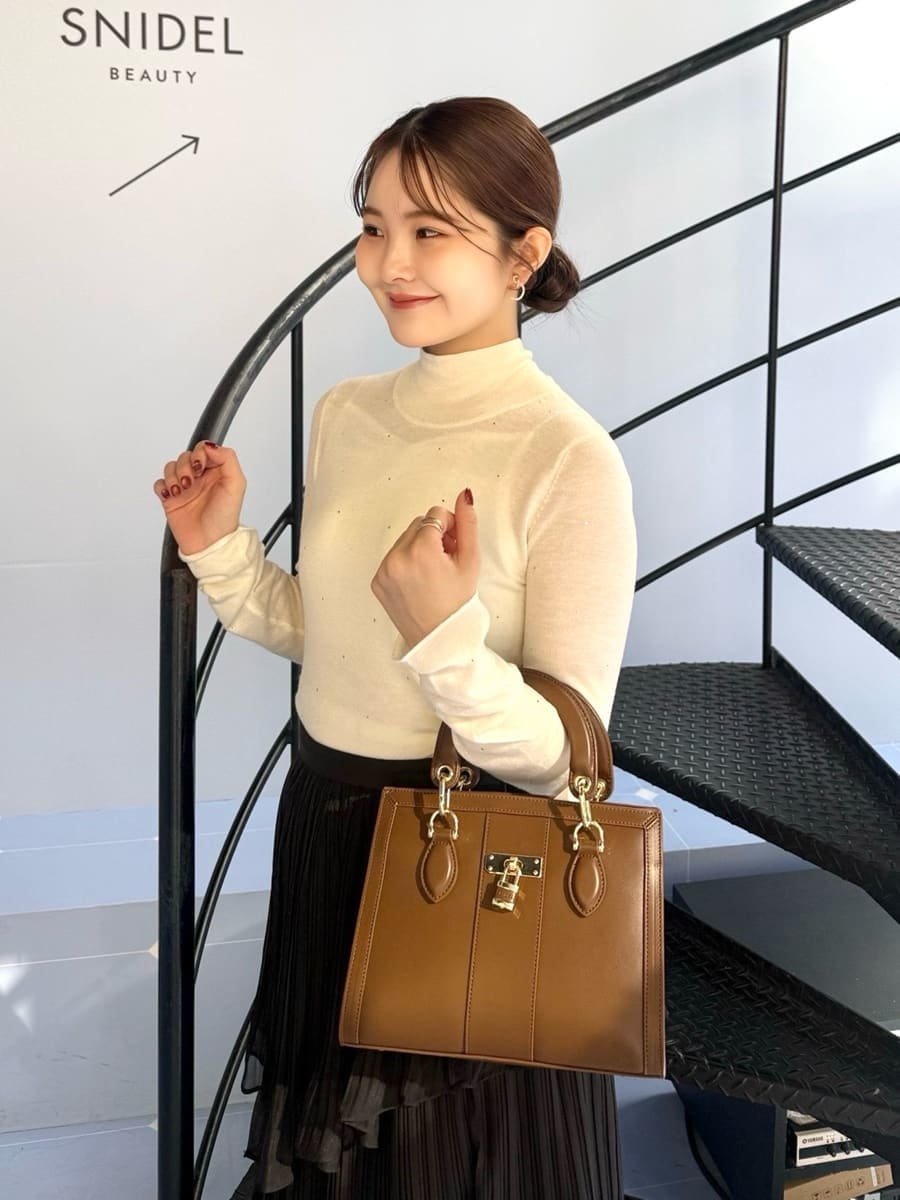 グレー系のダウンジャケット/コート、グレー系のスカート、ホワイト系のニット/セーターを着用したレディースの冬コーディネートの6枚目の写真