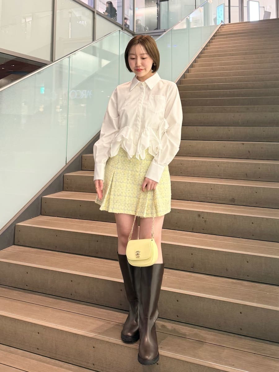 イエロー系のスカート、ホワイト系のシャツ/ブラウス、イエロー系のショルダーバッグを着用したレディースの冬コーディネートの9枚目の写真