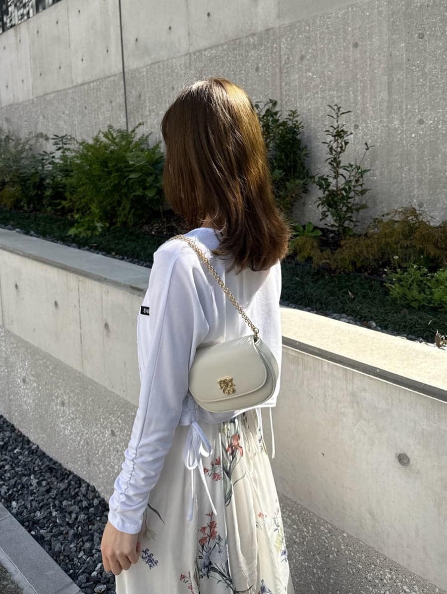 ホワイト系のワンピース、ブラウン系のパンプス、ホワイト系のショルダーバッグを着用したレディースの春コーディネートの3枚目の写真