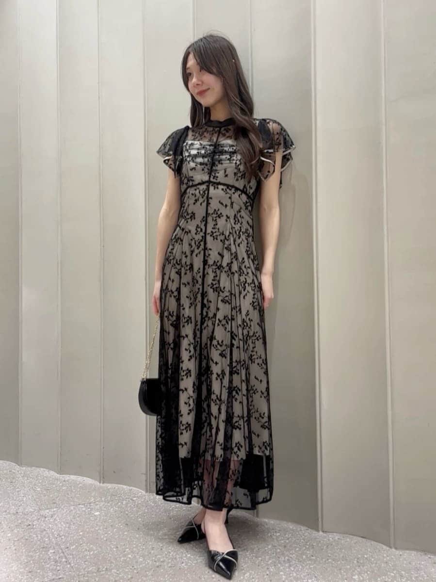 ブラック系のパンプス、ブラック系のショルダーバッグ、ブラック系のドレスを着用したレディースの春コーディネートの2枚目の写真