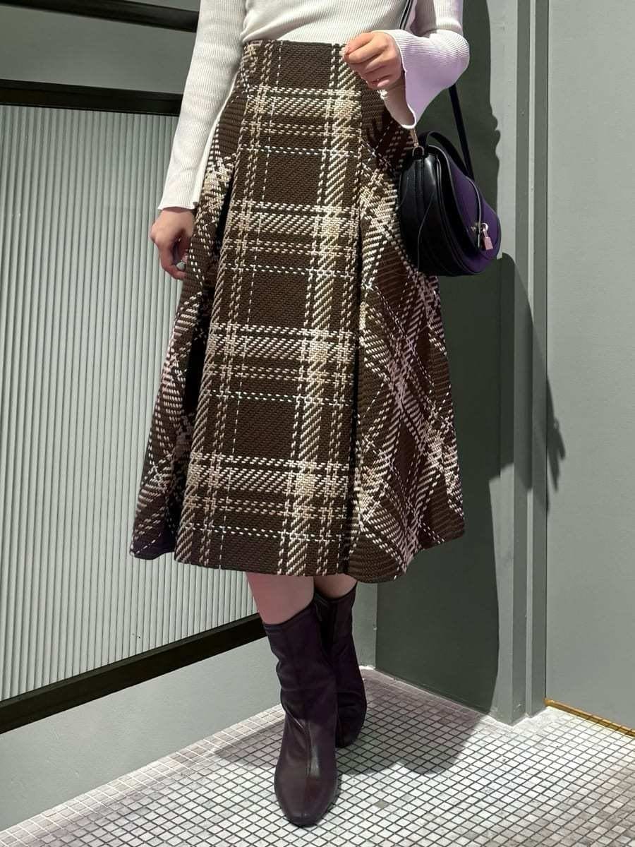 ホワイト系のニット/セーター、ブラウン系のスカート、レッド系のブーツを着用したレディースの秋コーディネートの4枚目の写真