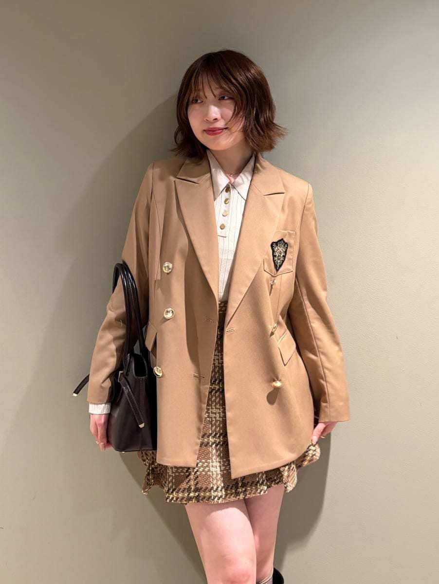 イエロー系のスカート、ベージュ系のポロシャツ、ブラウン系のブーツを着用したレディースの秋コーディネートの7枚目の写真