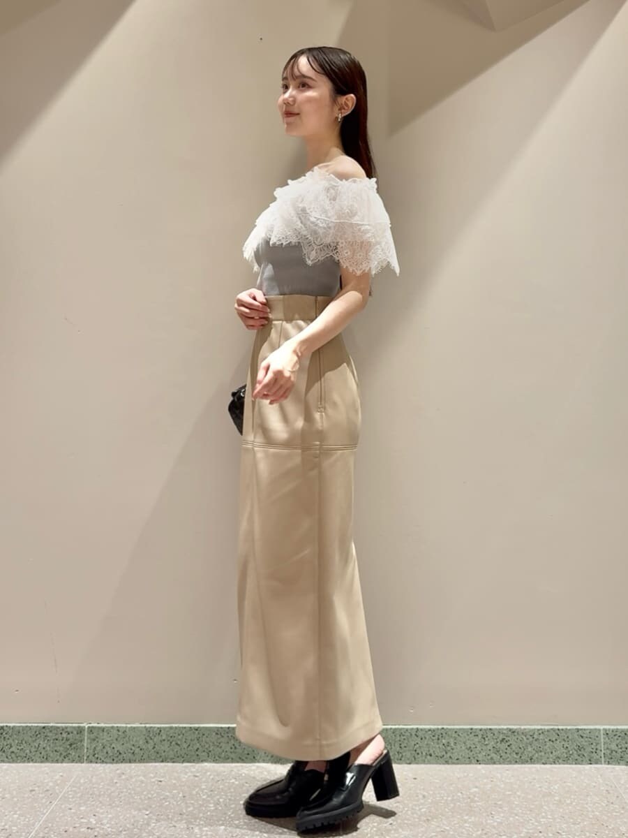 グリーン系のニット/セーター、ホワイト系のスカート、ブラック系のローファーを着用したレディースの夏コーディネートの2枚目の写真