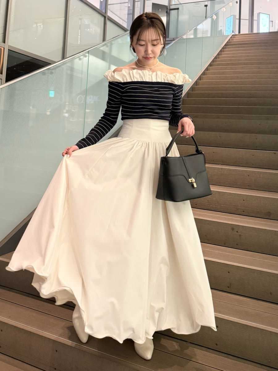 ベージュ系のトレンチコート、ホワイト系のスカート、その他のニット/セーターを着用したレディースの冬コーディネートの3枚目の写真