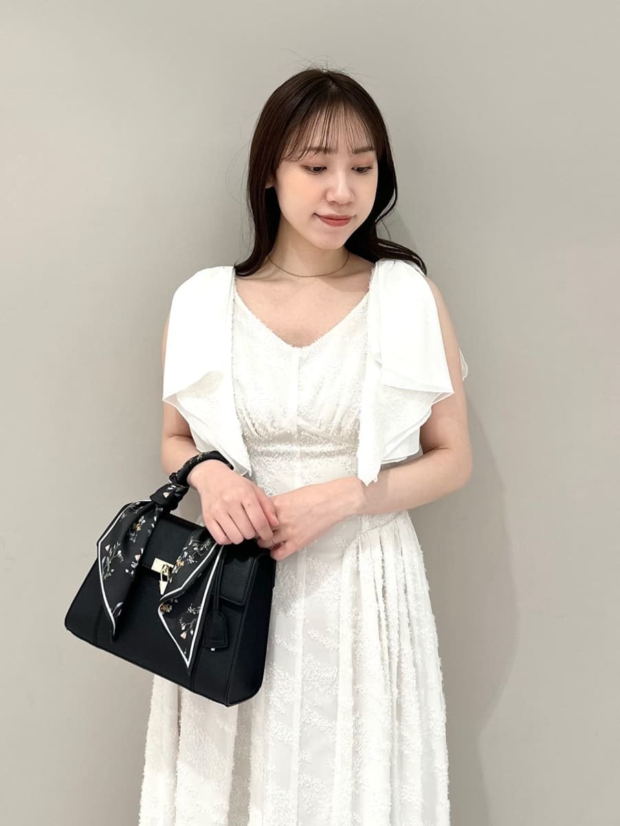 ホワイト系のワンピース、ブラック系のハンドバッグ、ブラック系のパンプスを着用したレディースの春コーディネートの2枚目の写真