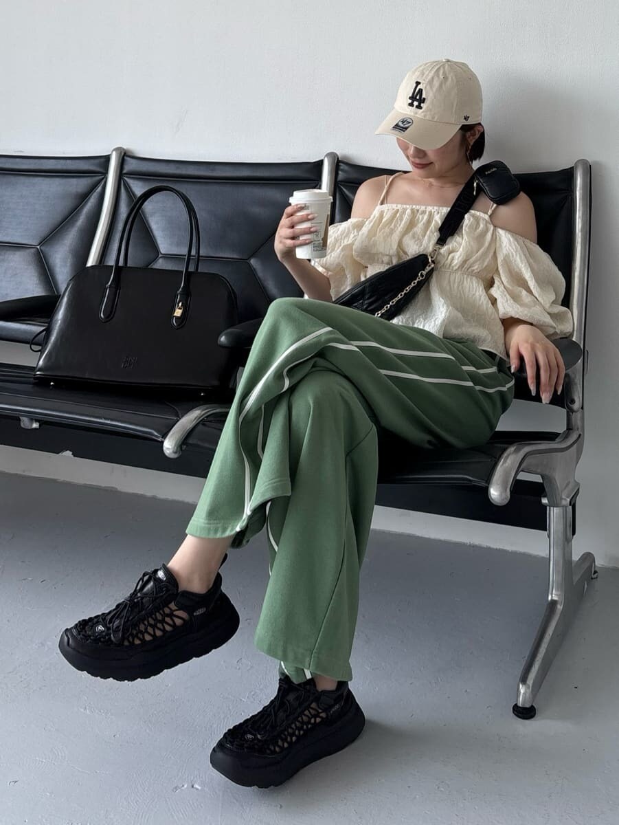 グリーン系のスウェットパンツ、ブラック系のショルダーバッグ、ブラック系のサンダルを着用したレディースの夏コーディネートの4枚目の写真