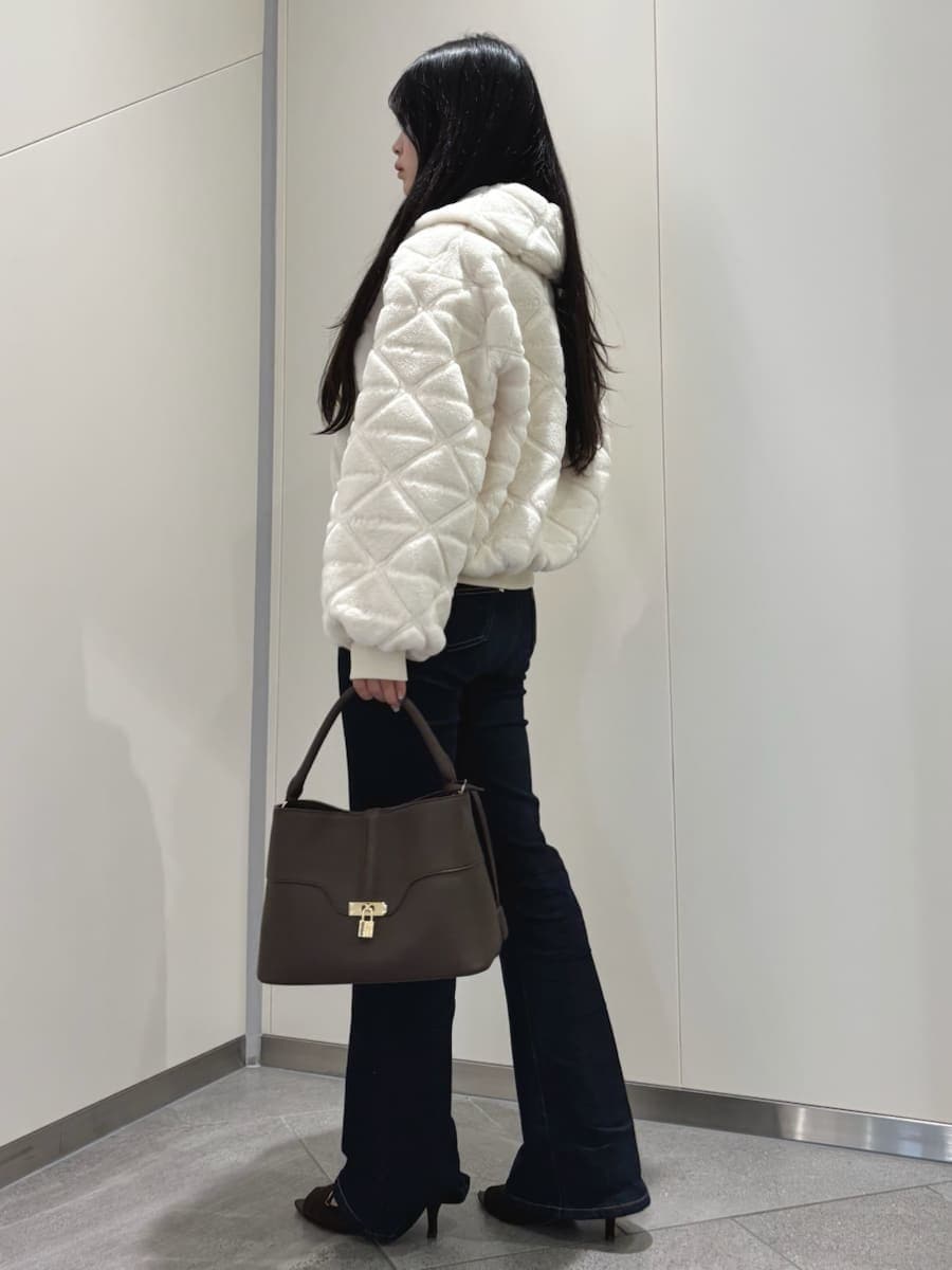 ブラウン系のハンドバッグ、ブルー系のデニムパンツ、ホワイト系のブルゾンを着用したレディースの秋コーディネートの2枚目の写真