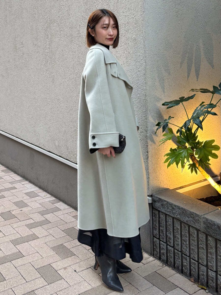 グレー系のブーツ、グリーン系のチェスターコート、ブラック系のワンピースを着用したレディースの秋コーディネートの4枚目の写真