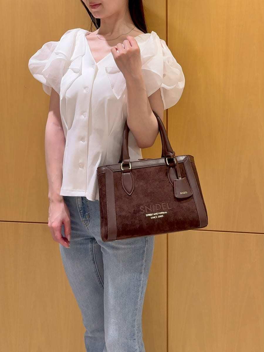 ブルー系のデニムパンツ、ホワイト系のTシャツ/カットソー、ブラウン系のハンドバッグを着用したレディースの夏コーディネートの7枚目の写真