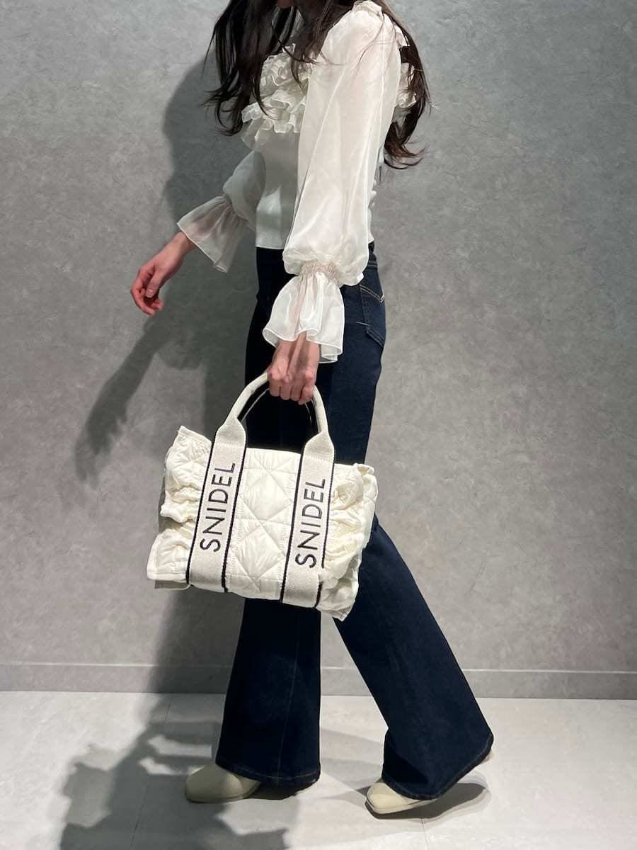 ブルー系のその他パンツ、ホワイト系のニット/セーター、ホワイト系のハンドバッグを着用したレディースの冬コーディネートの4枚目の写真