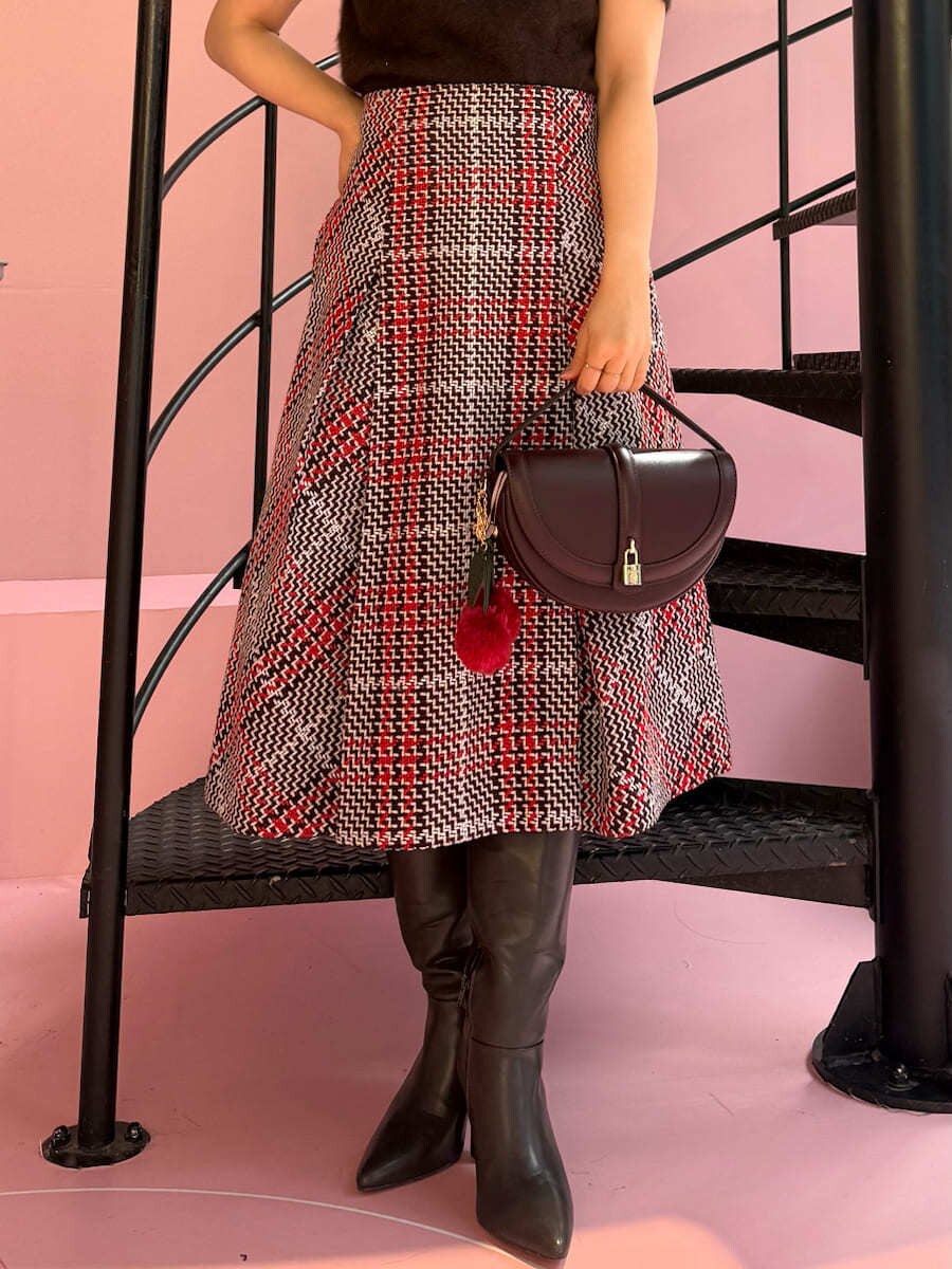 ブラウン系のニット/セーター、レッド系のスカート、ブラウン系のブーツを着用したレディースの秋コーディネートの6枚目の写真