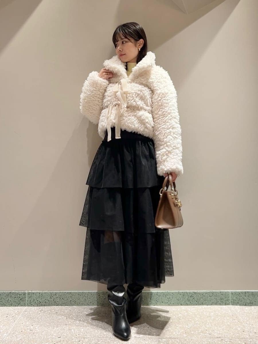 イエロー系のニット/セーター、ホワイト系のムートンコート、ブラック系のスカートを着用したレディースの秋コーディネートの3枚目の写真