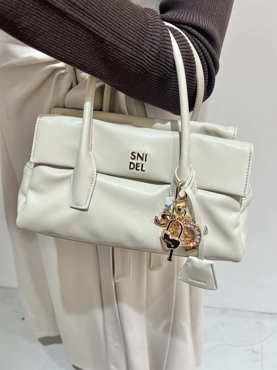 ブラウン系のステンカラーコート、ベージュ系のワンピース、ブラウン系のニット/セーターを着用したレディースの秋コーディネートの10枚目の写真