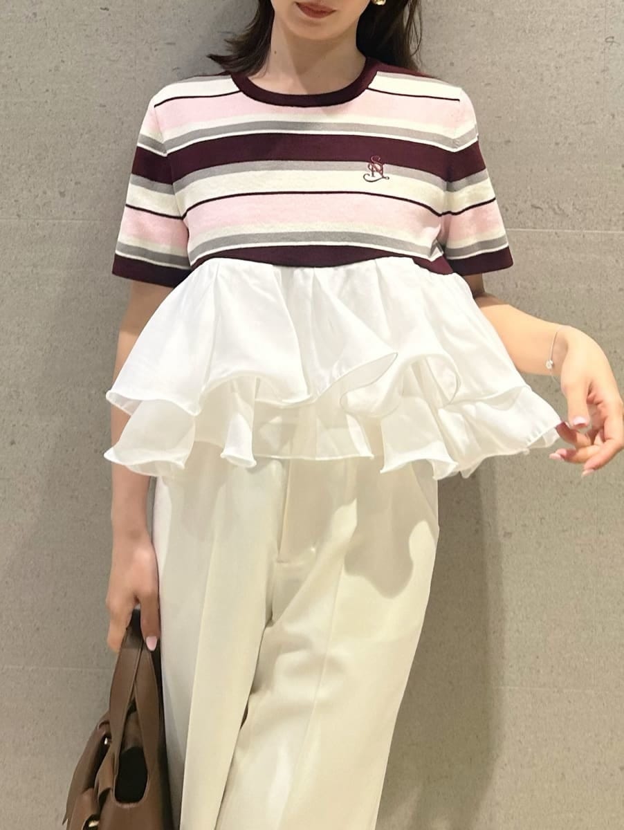 ホワイト系のスラックス、ピンク系のTシャツ/カットソー、ブラウン系のハンドバッグを着用したレディースの春コーディネートの4枚目の写真