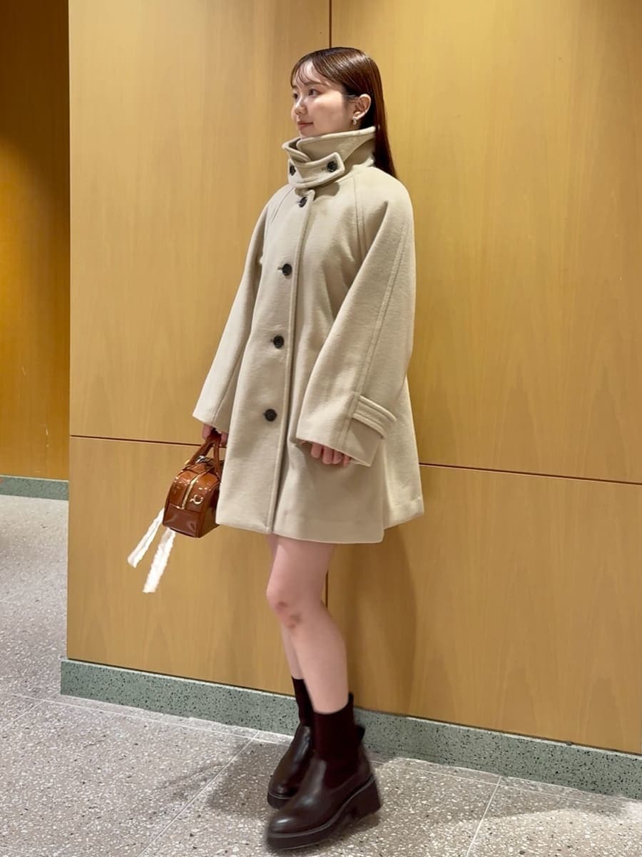 ベージュ系のステンカラーコート、ブルー系のその他トップス、ブラウン系のボストンバッグを着用したレディースの秋コーディネートの3枚目の写真