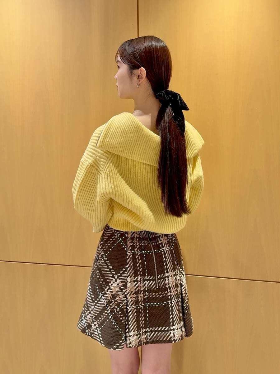 ブラウン系のスカート、イエロー系のニット/セーター、ブラウン系のブーツを着用したレディースの冬コーディネートの2枚目の写真