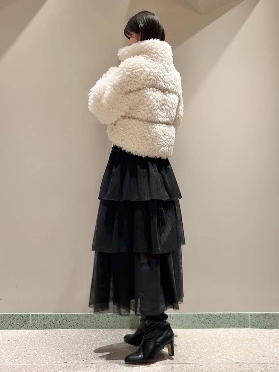 イエロー系のニット/セーター、ホワイト系のムートンコート、ブラック系のスカートを着用したレディースの秋コーディネートの2枚目の写真