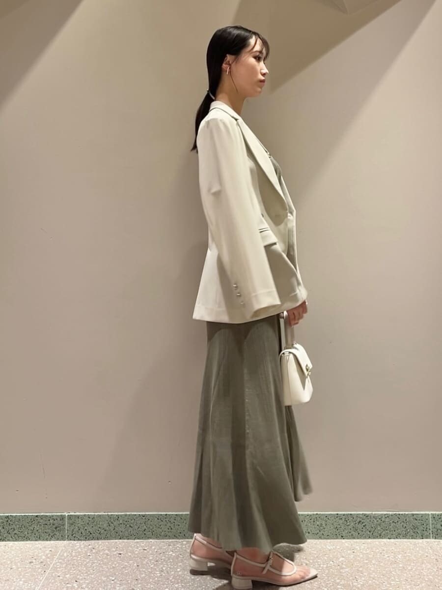 ベージュ系のテーラードジャケット、グリーン系のワンピース、ホワイト系のショルダーバッグを着用したレディースの夏コーディネートの4枚目の写真