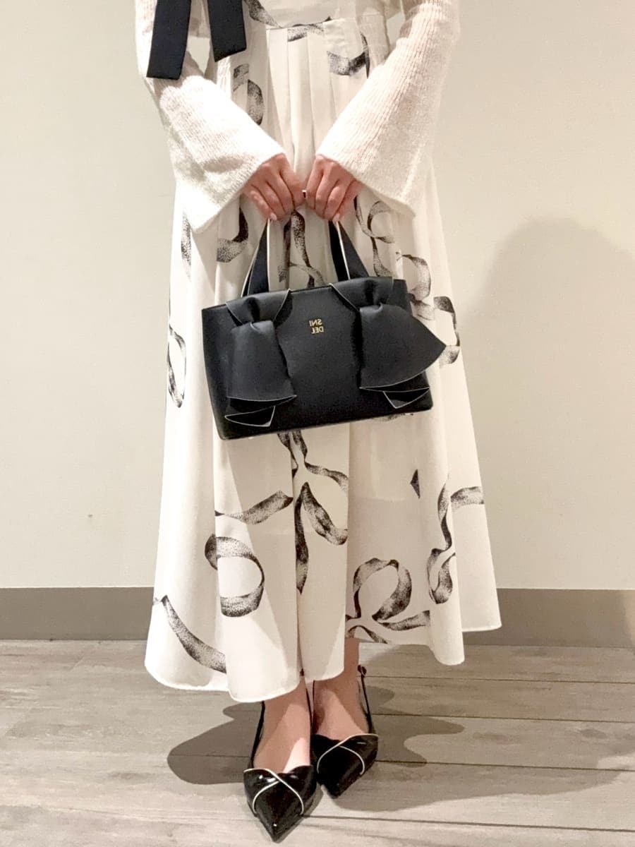 ホワイト系のワンピース、ブラック系のパンプス、ブラック系のハンドバッグを着用したレディースの冬コーディネートの4枚目の写真