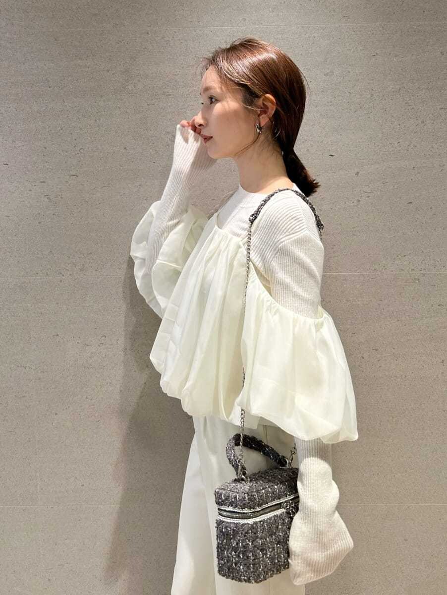 ブラウン系のブーツ、ホワイト系のスラックス、ホワイト系のニット/セーターを着用したレディースの秋コーディネートの2枚目の写真