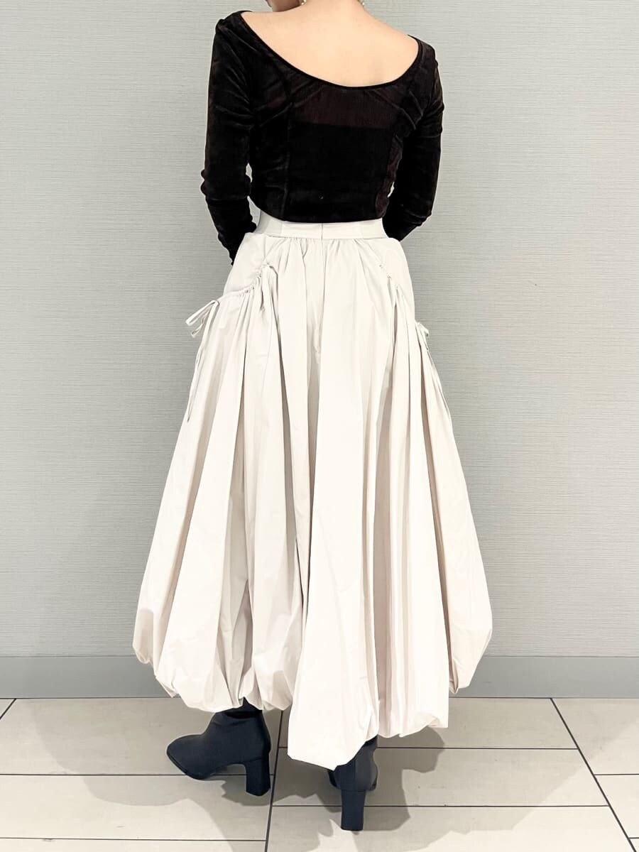 ベージュ系のスカート、ブラウン系のTシャツ/カットソー、ベージュ系のチェスターコートを着用したレディースの秋コーディネートの3枚目の写真