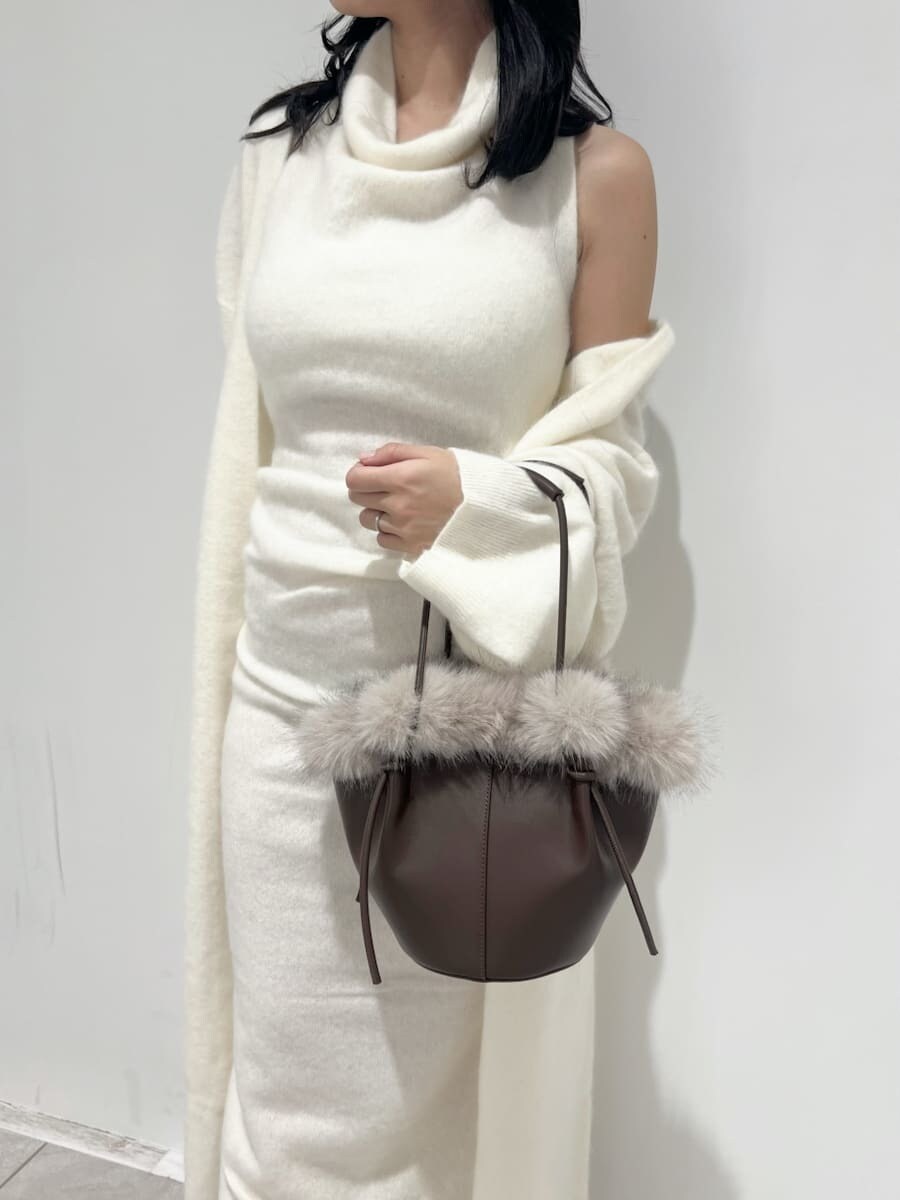 ホワイト系のチェスターコート、ホワイト系のワンピース、ブラウン系のハンドバッグを着用したレディースの冬コーディネートの4枚目の写真