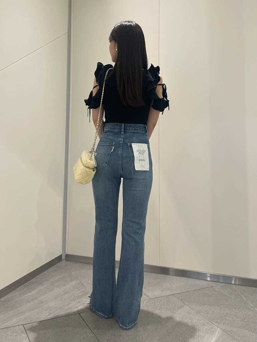 ブラック系のニット/セーター、ブルー系のデニムパンツ、イエロー系のスマホグッズを着用したレディースの夏コーディネートの3枚目の写真