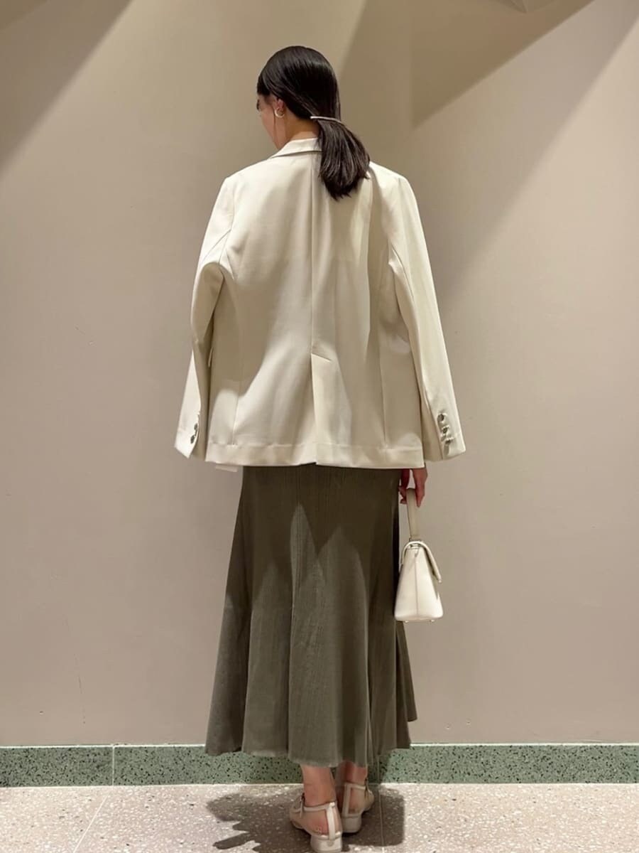 ベージュ系のテーラードジャケット、グリーン系のワンピース、ホワイト系のショルダーバッグを着用したレディースの夏コーディネートの5枚目の写真