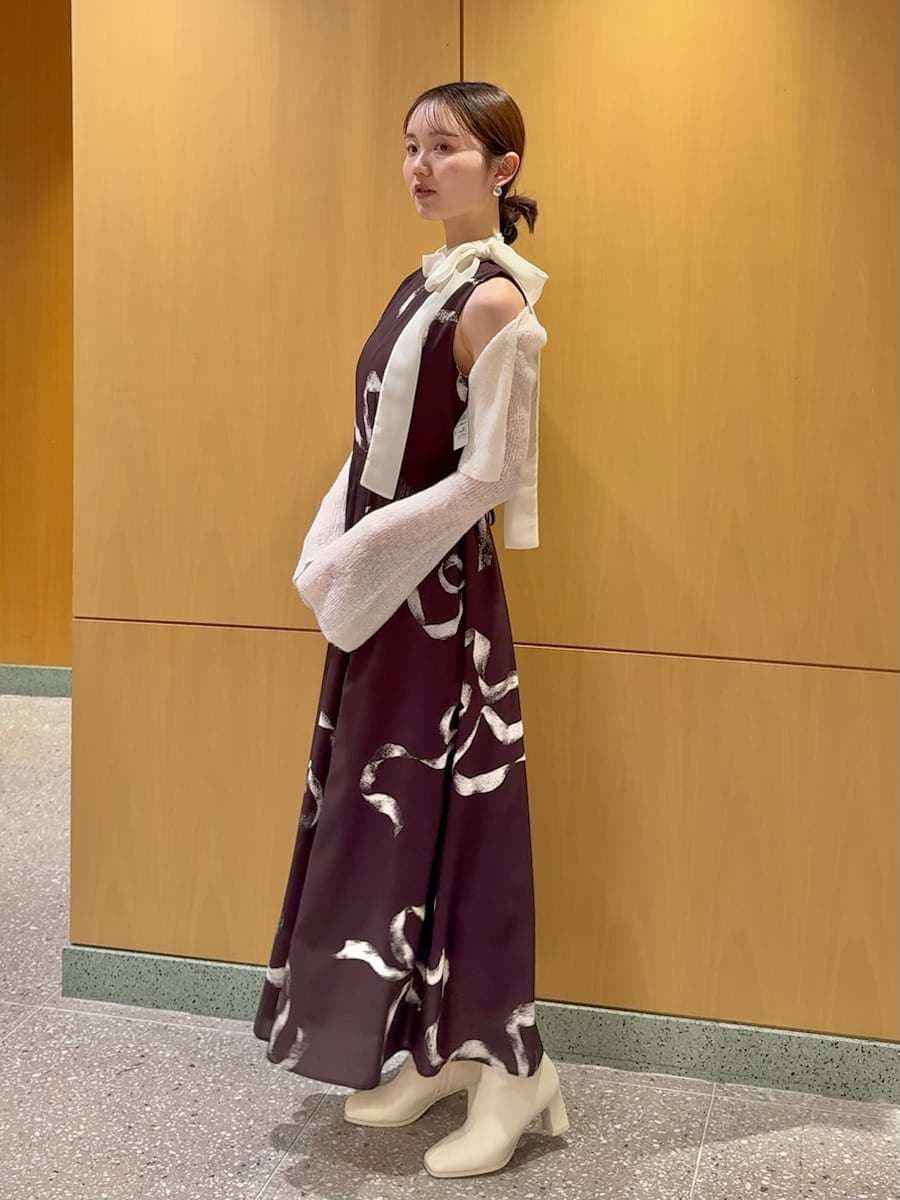 ホワイト系のショルダーバッグ、ブラウン系のワンピース、シルバー系のピアス（両耳用）を着用したレディースの冬コーディネートの2枚目の写真