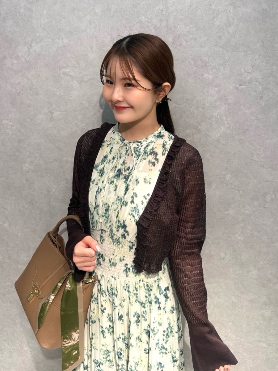 イエロー系のハンドバッグ、グリーン系のワンピース、ブラウン系のカーディガン/ボレロを着用したレディースの冬コーディネートの7枚目の写真