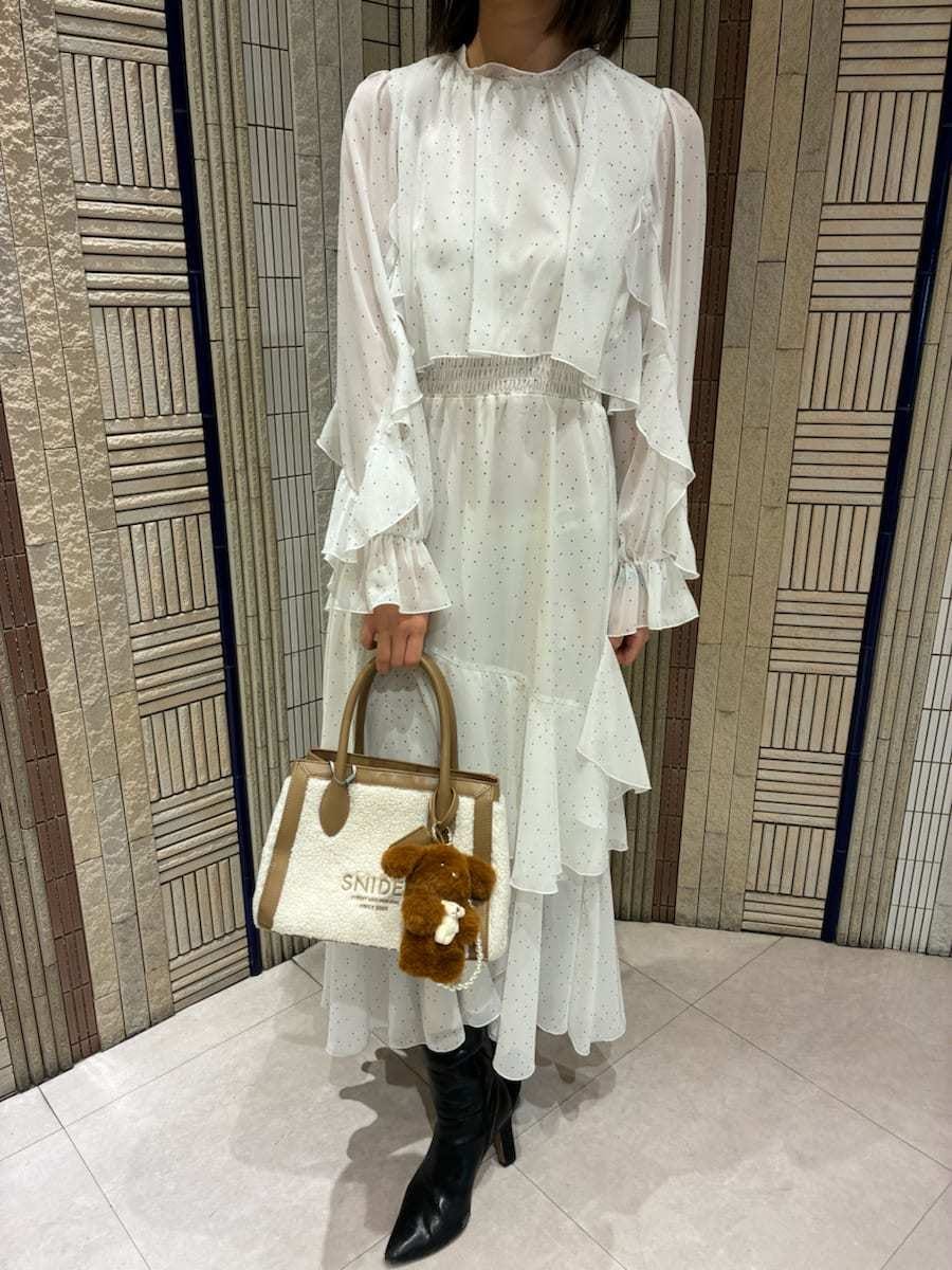 イエロー系のトートバッグ、ブラック系のブーツ、その他のワンピースを着用したレディースの冬コーディネートの5枚目の写真