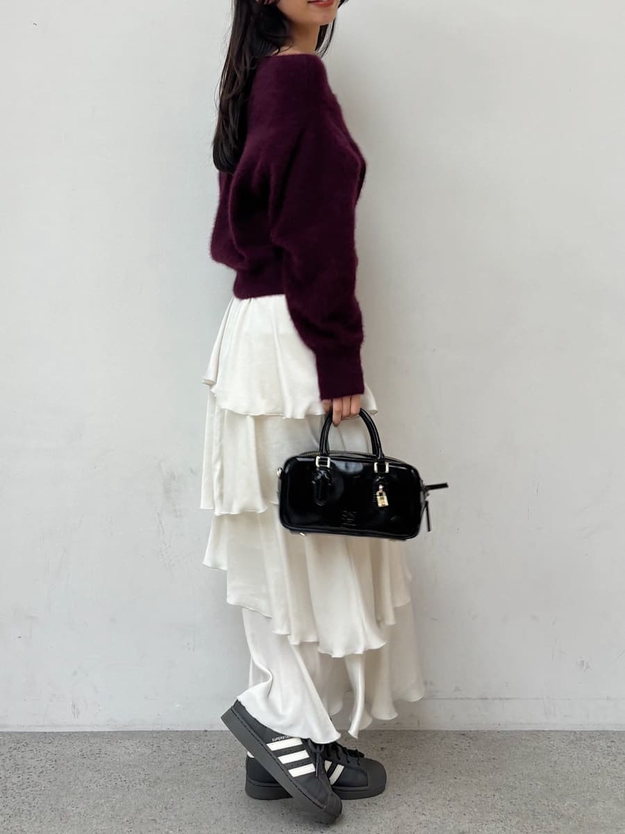 レッド系のニット/セーター、ホワイト系のスカート、グレー系のスニーカーを着用したレディースの秋コーディネートの3枚目の写真