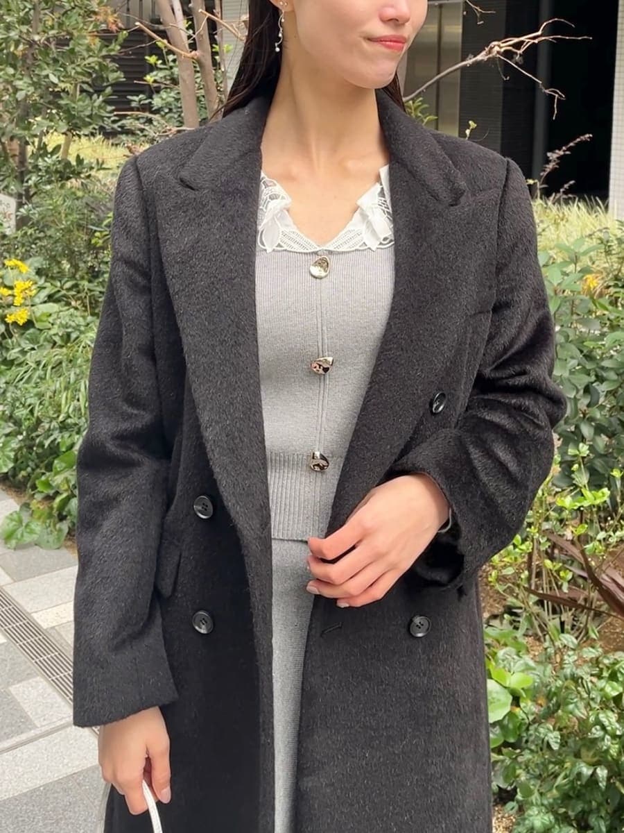 ブラック系のチェスターコート、グレー系のワンピースを着用したレディースの冬コーディネートの2枚目の写真