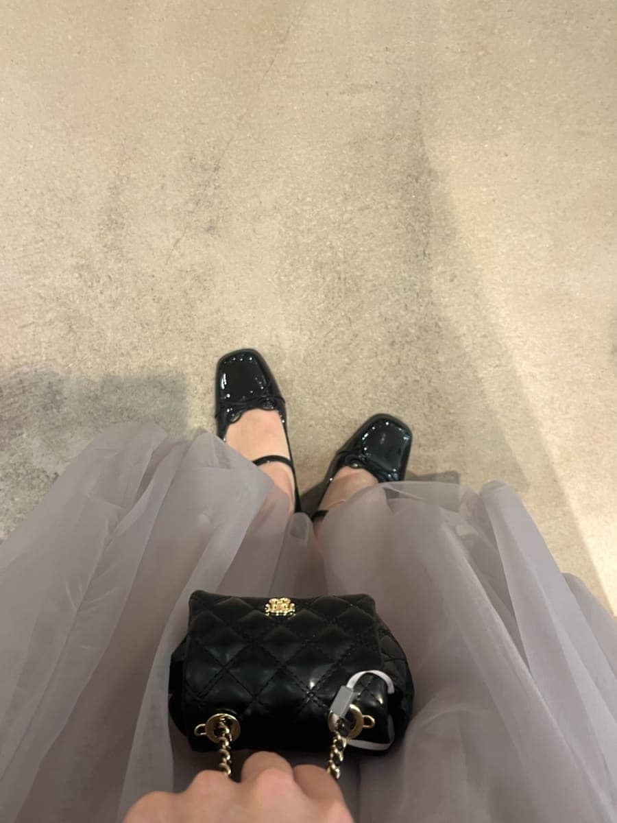 パープル系のワンピース、ブラック系のパンプス、ブラック系のショルダーバッグを着用したレディースの秋コーディネートの5枚目の写真