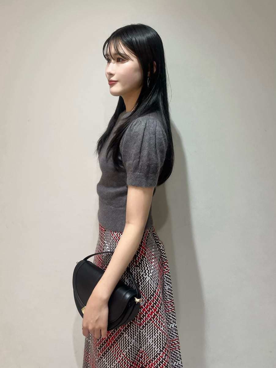 グレー系のニット/セーター、レッド系のスカート、ブラック系のハンドバッグを着用したレディースの秋コーディネートの5枚目の写真