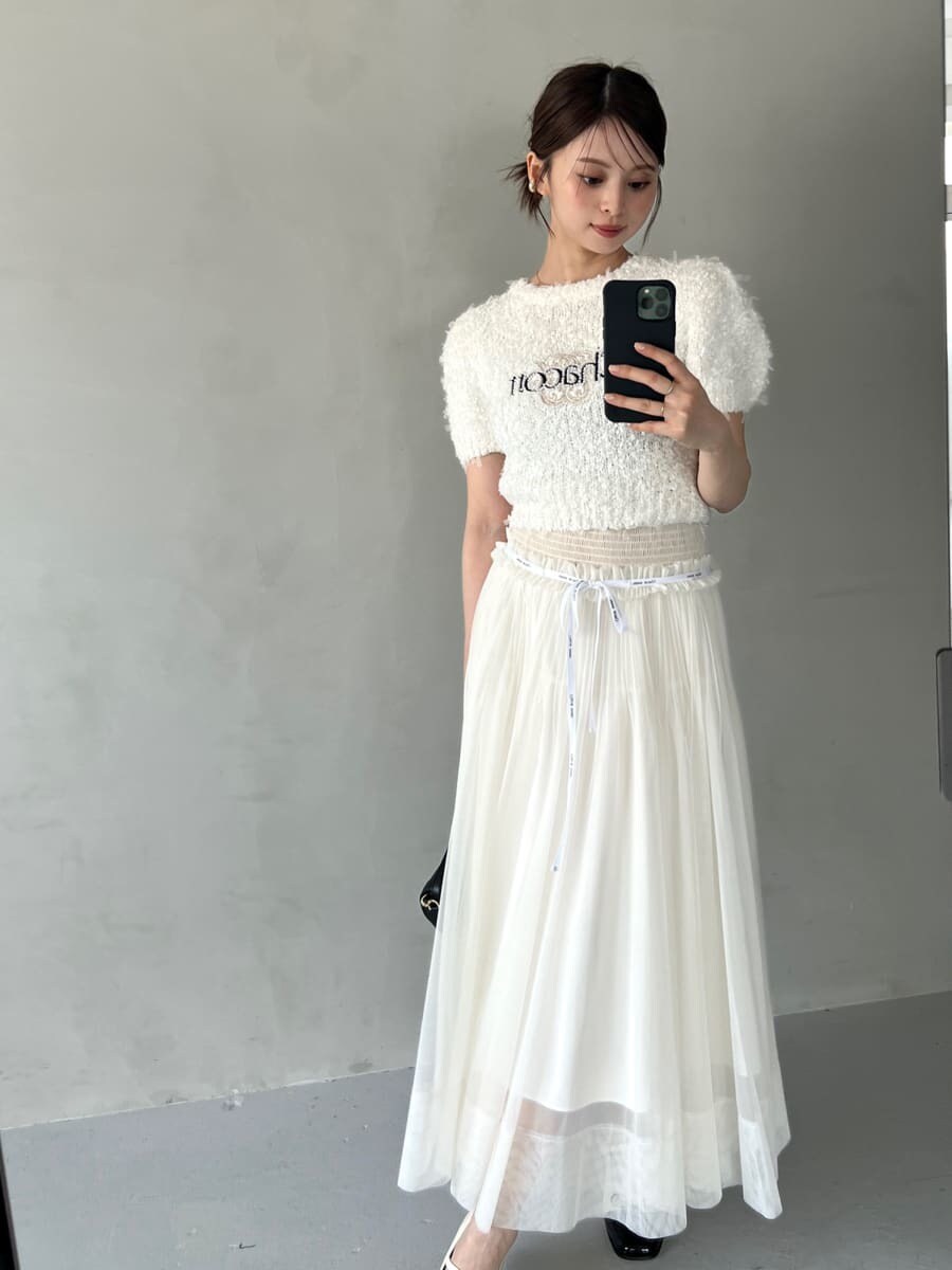 ホワイト系のニット/セーター、ホワイト系のスカート、ブラック系のハンドバッグを着用したレディースの夏コーディネートの2枚目の写真