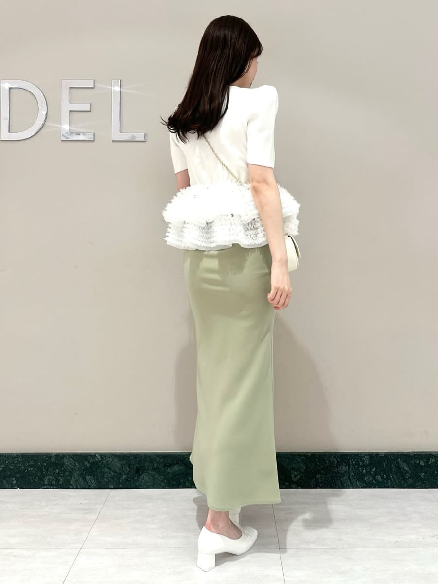 グリーン系のスカート、ホワイト系のニット/セーター、ホワイト系のショルダーバッグを着用したレディースの春コーディネートの5枚目の写真