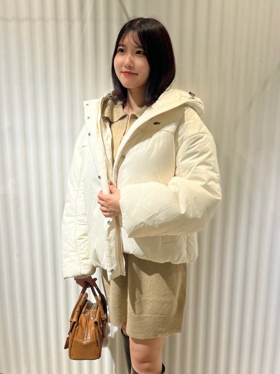 ホワイト系のダウンジャケット/コート、ブラウン系のブーツ、イエロー系のボストンバッグを着用したレディースの秋コーディネートの2枚目の写真