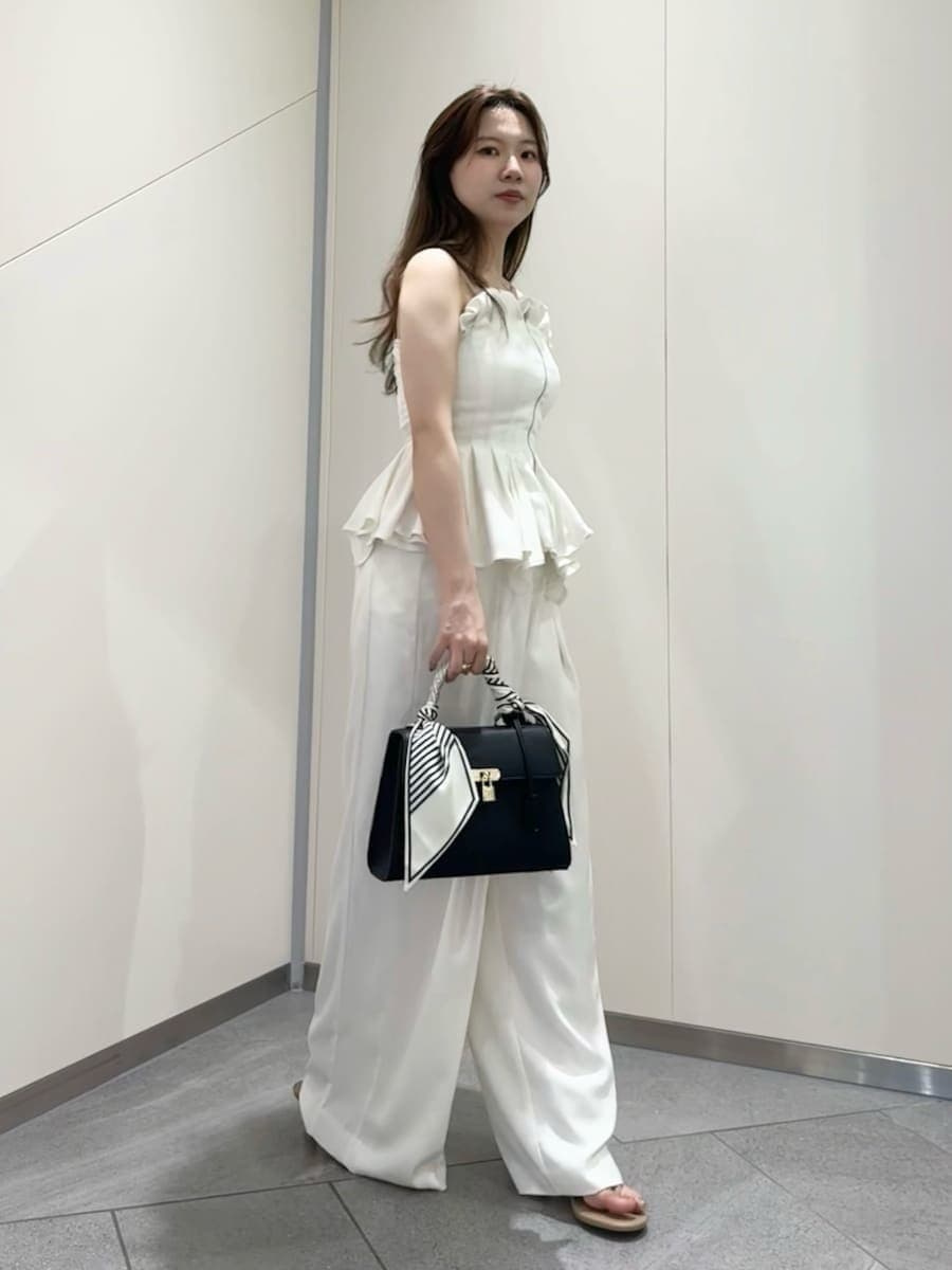 ブラック系のハンドバッグ、ホワイト系のその他パンツ、ホワイト系のその他トップスを着用したレディースの夏コーディネートの3枚目の写真
