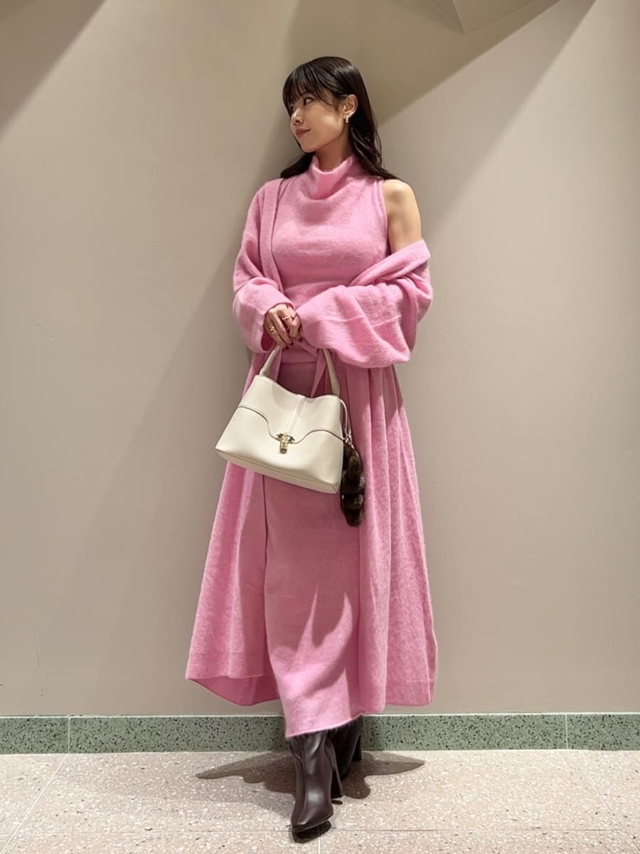 レッド系のブーツ、ピンク系のチェスターコート、ピンク系のワンピースを着用したレディースの冬コーディネートの4枚目の写真