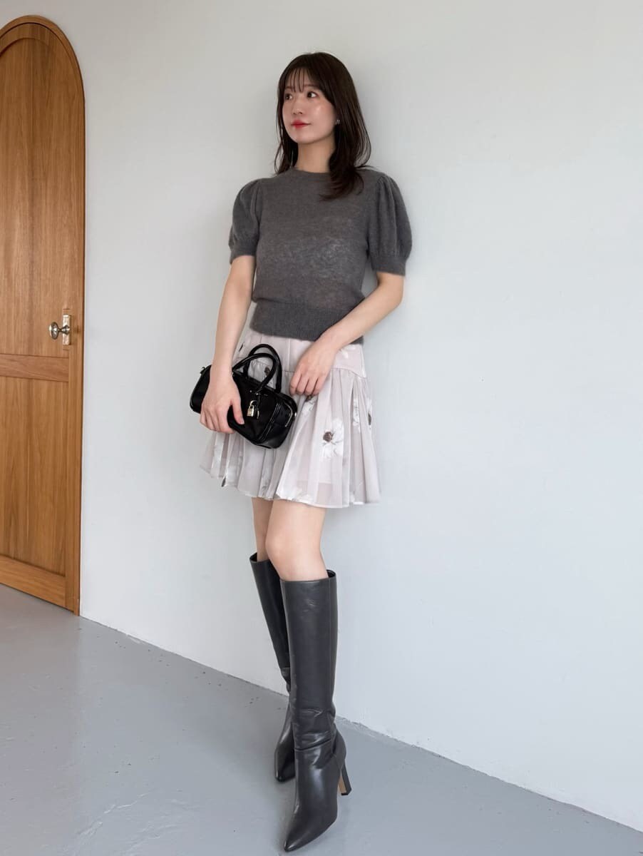 グレー系のニット/セーター、ブラック系のボストンバッグ、グレー系のブーツを着用したレディースの夏コーディネートの2枚目の写真
