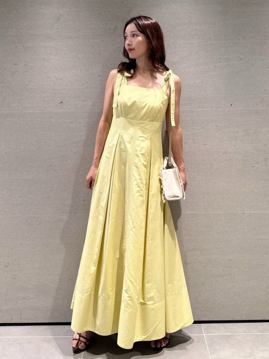 イエロー系のワンピース、ベージュ系のショルダーバッグ、ブラウン系のサンダルを着用したレディースの夏コーディネートの3枚目の写真