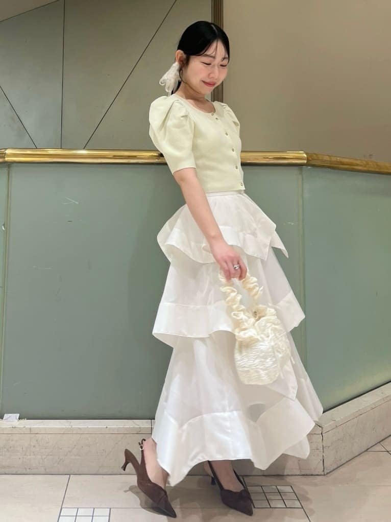 ホワイト系のスカート、イエロー系のカーディガン/ボレロ、ブラウン系のパンプスを着用したレディースの春コーディネートの3枚目の写真