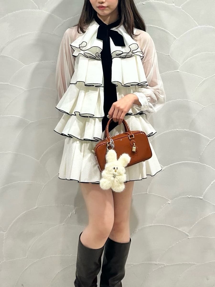 ブラウン系のボストンバッグ、ホワイト系のドレス、イエロー系のキーケース/キーアクセサリーを着用したレディースの冬コーディネートの2枚目の写真