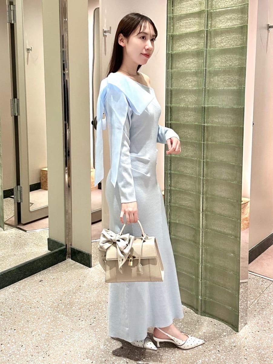 ブルー系のワンピース、その他のパンプス、ベージュ系のハンドバッグを着用したレディースの冬コーディネートの3枚目の写真